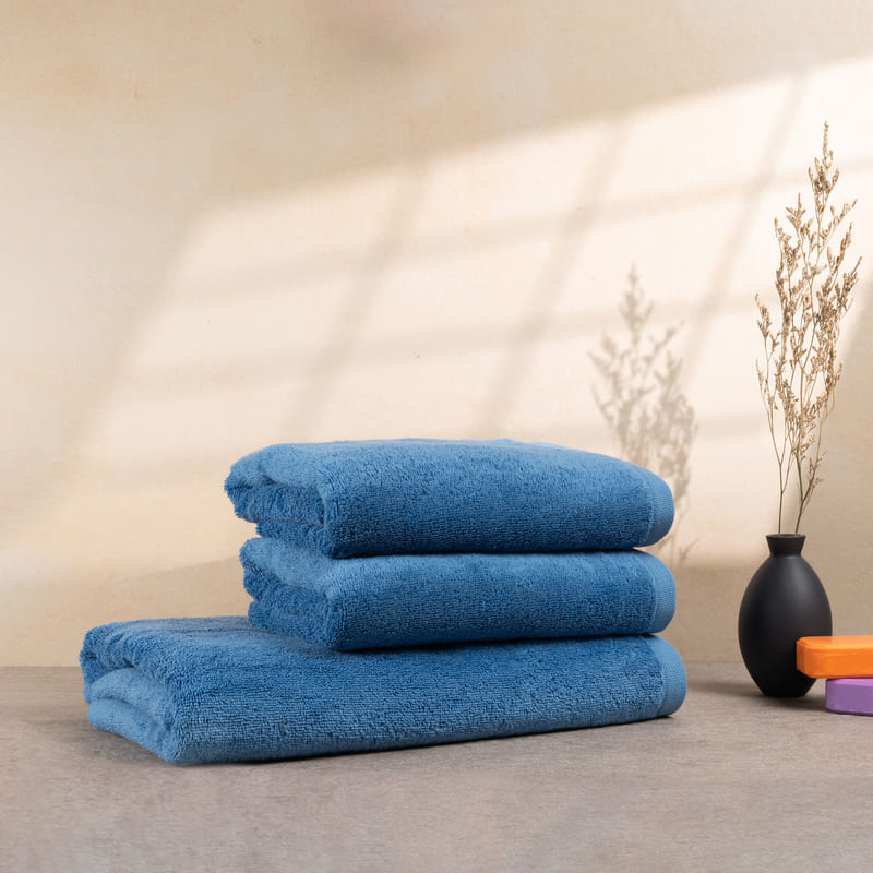 Set aus 3 weichen, hellblauen Handtüchern, ordentlich gestapelt auf einem Tisch – verleiht jedem Badezimmer einen Hauch von Eleganz.