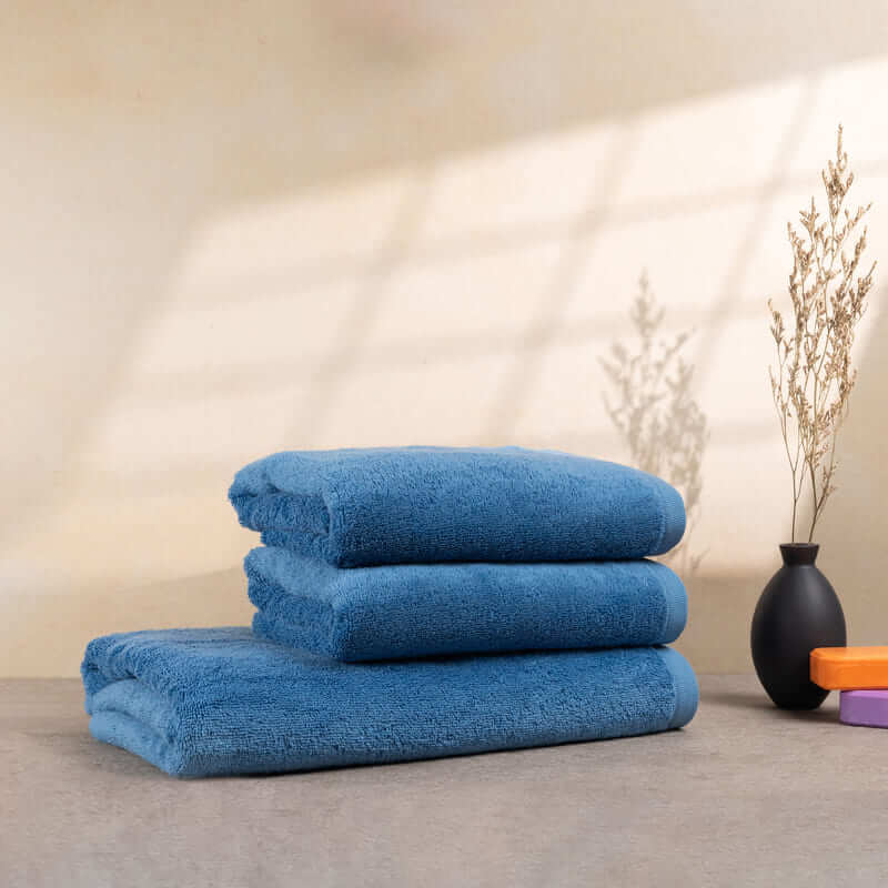 Set aus 3 weichen, hellblauen Handtüchern, ordentlich gestapelt auf einem Tisch – verleiht jedem Badezimmer einen Hauch von Eleganz.