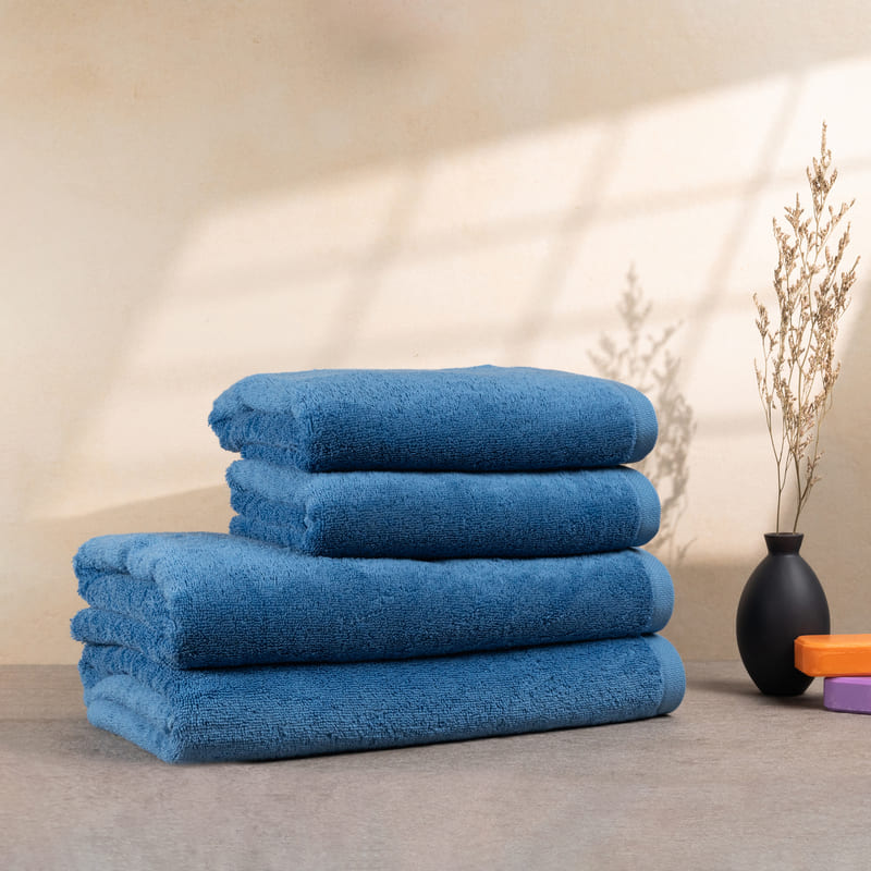 Set aus 4 hellblauen Handtüchern, gestapelt auf einem Tisch – mit flauschiger Struktur und lebendiger Farbe.