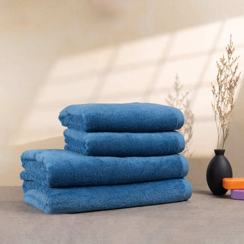 Set aus 4 hellblauen Handtüchern, gestapelt auf einem Tisch – mit flauschiger Struktur und lebendiger Farbe.