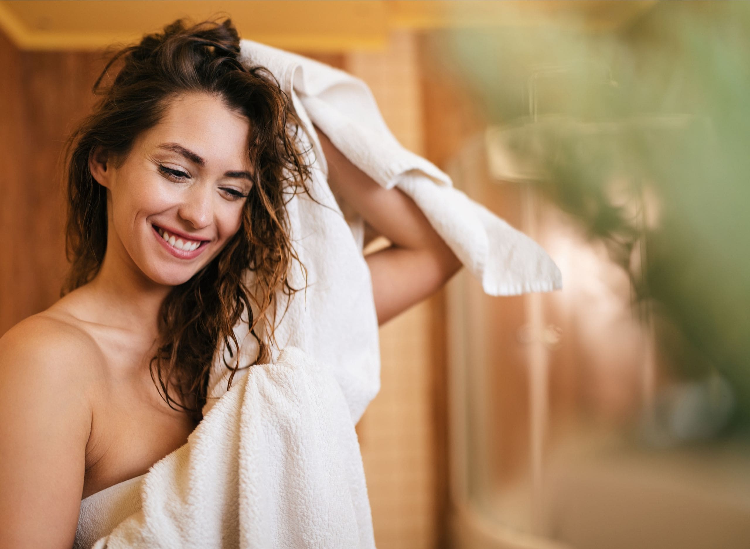 Nachhaltige Luxus Handtücher von Bomlins eine Frau die Ihr weiches Handtuch im Bad genießt.
