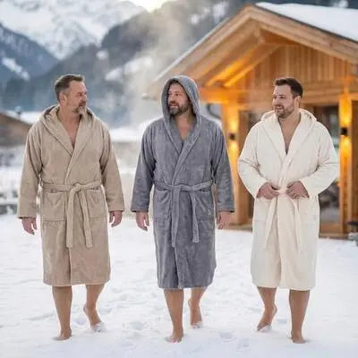 Herren in drei verschiedenen Bomlins Bademänteln XXL aus GIZA Baumwolle (Cashmere, Beige, Grau und Naturweiß) gehen barfuß durch den Schnee vor einer Berghütte.