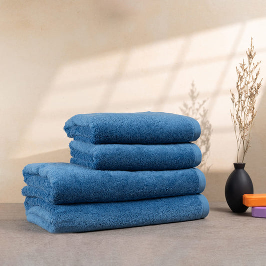 Set aus 4 hellblauen Handtüchern, gestapelt auf einem Tisch – mit flauschiger Struktur und lebendiger Farbe.