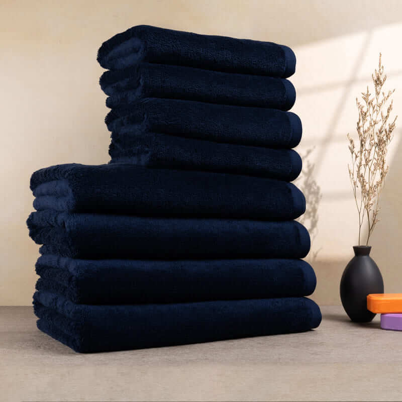 Set aus 8 dunkelblauen Handtüchern, ordentlich gestapelt – mit weicher und flauschiger Textur.